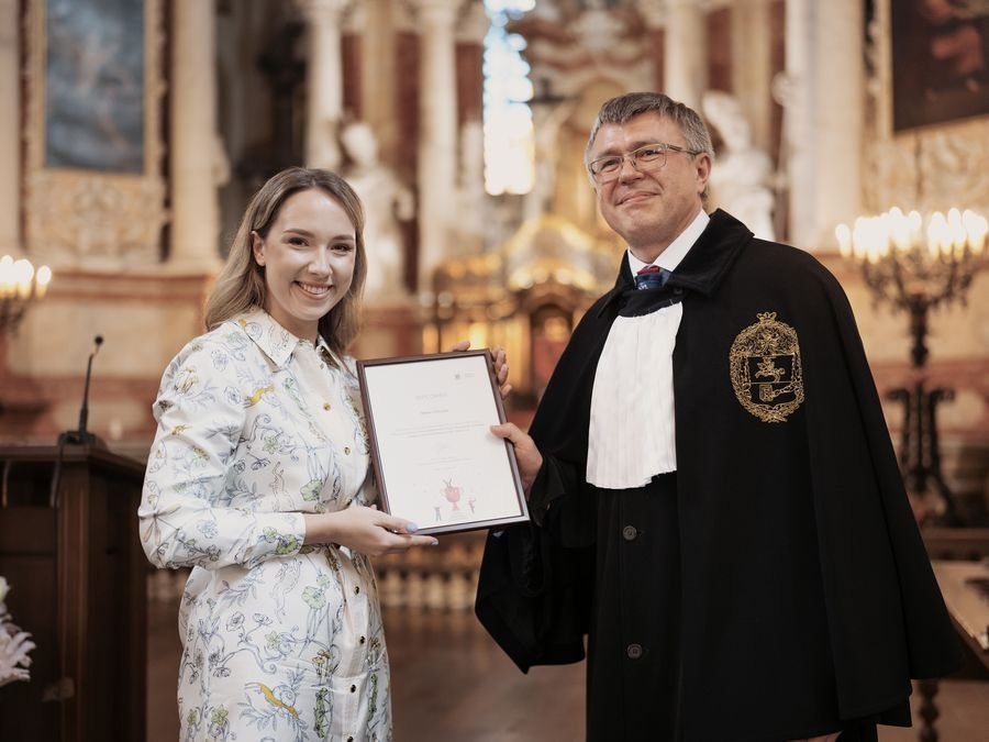Milda Vitosytė receiving a framed diploma at a Vilnius University ceremony